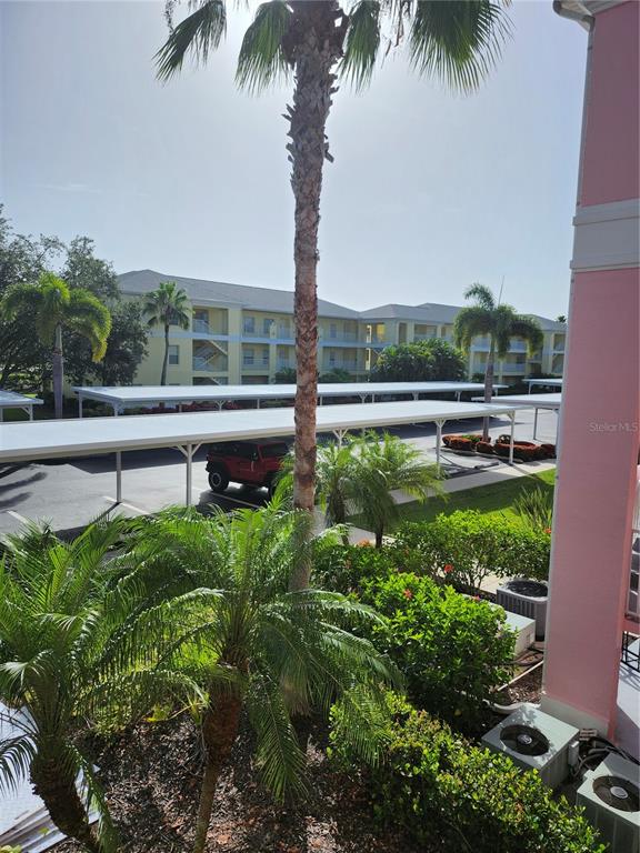 An elevated view of a parking lot with covered carports, palm trees, and apartment buildings — 2061 WILLOW HAMMOCK CIRCLE UNIT 202, PORT CHARLOTTE, FL