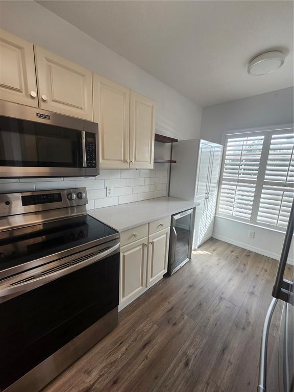 A kitchen features cream cabinets, stainless steel appliances, white subway tile, and wood-look flooring — 2061 WILLOW HAMMOCK CIRCLE UNIT 202, PORT CHARLOTTE, FL