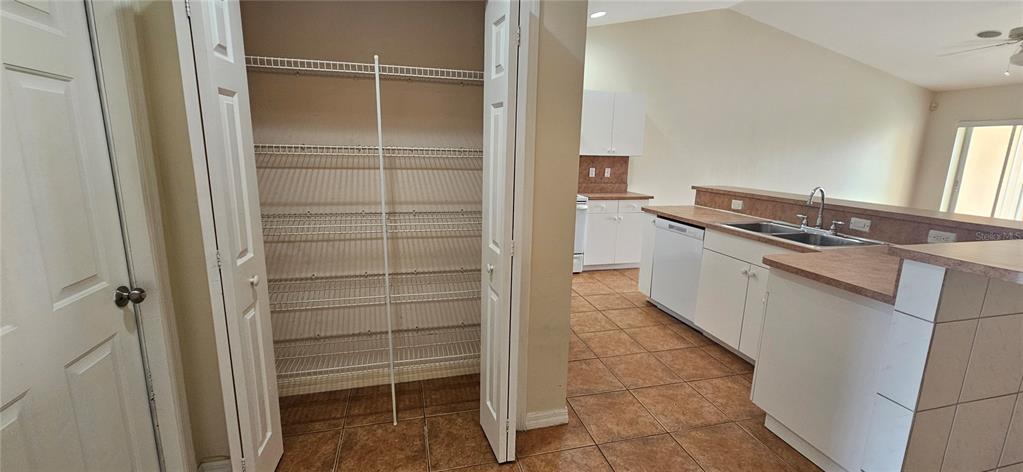 A kitchen features white cabinets, tile flooring, a pantry with wire shelving, and a sink — 3007 SW SANTA BARBARA PLACE, CAPE CORAL, FL
