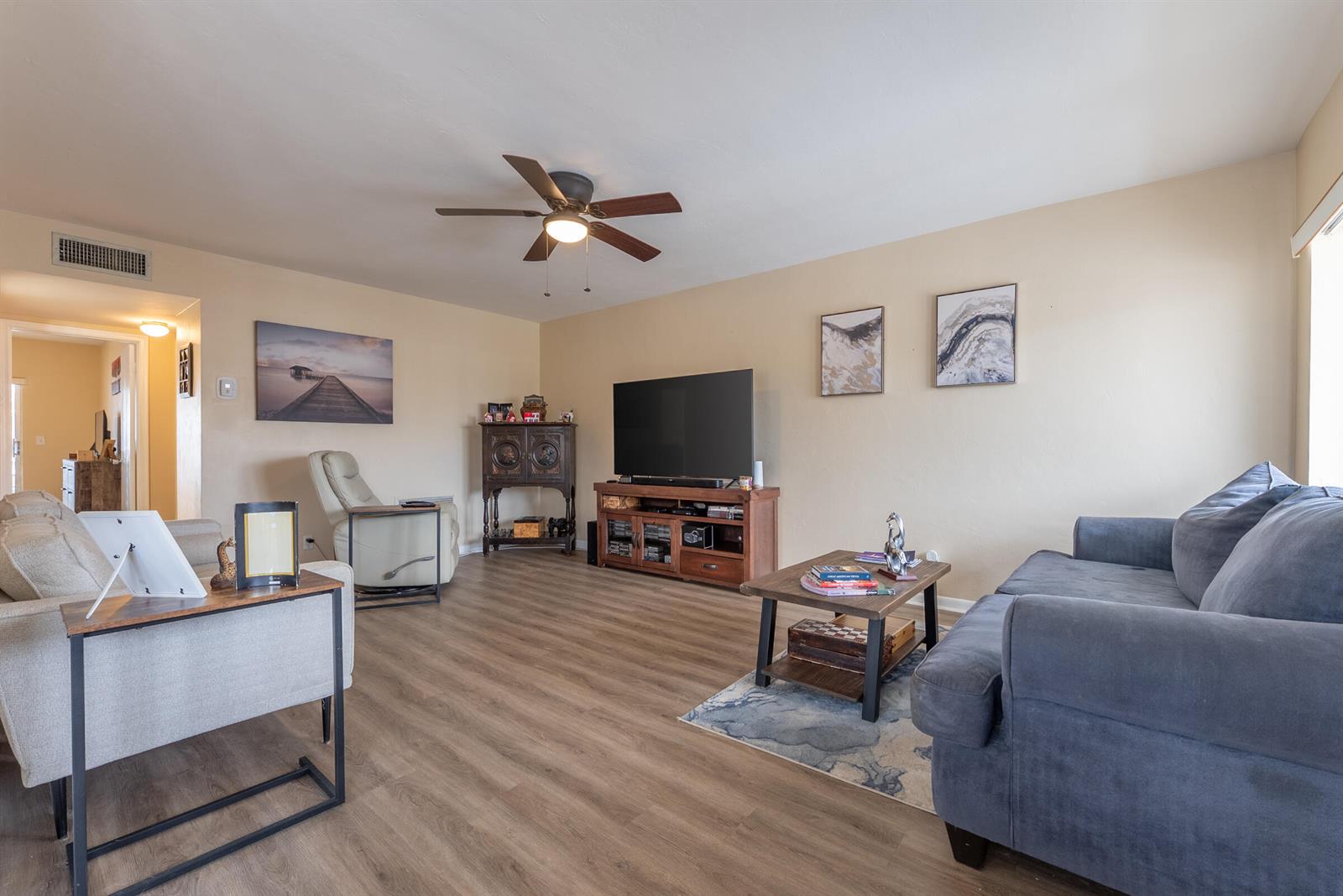 A living room features light wood-look flooring, a ceiling fan, a television, and two sofas — 2920 Cynthia Lane # 202, FL 33461, FL