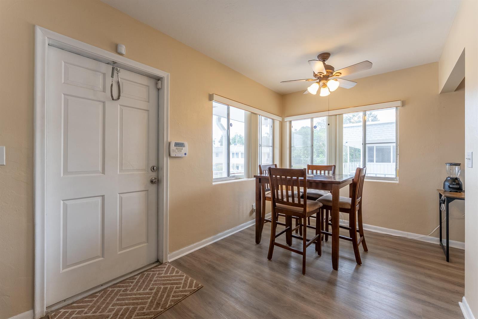 A dining area features a wooden table, four chairs, a ceiling fan, and a door — 2920 Cynthia Lane # 202, FL 33461, FL