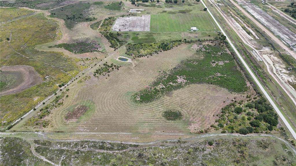 An aerial view shows a large, grassy plot of land with a small pond and trees — COUNTY LINE ROAD E, FORT MEADE, FL