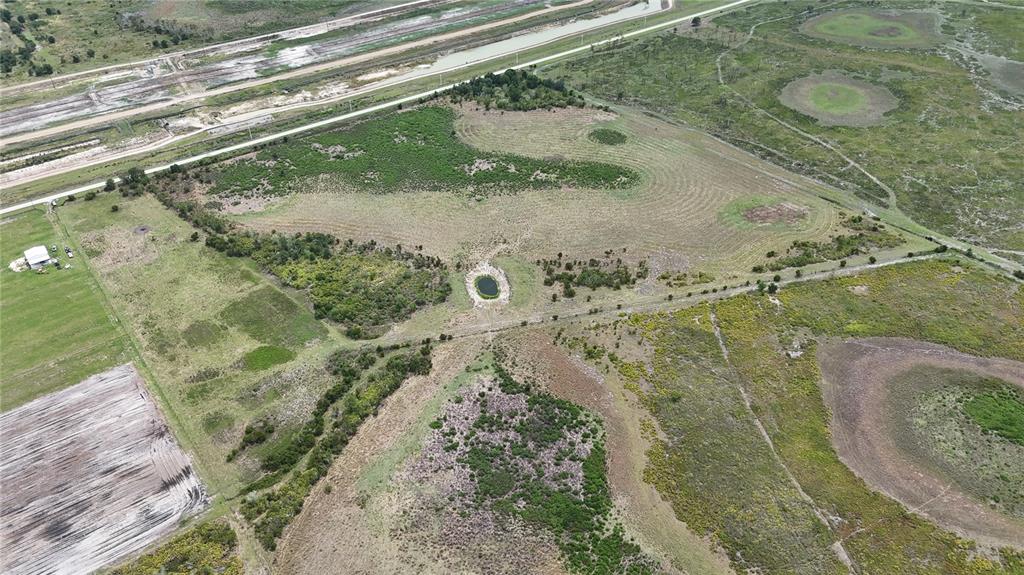 An aerial view shows a large, grassy plot of land featuring a small central pond — COUNTY LINE ROAD E, FORT MEADE, FL