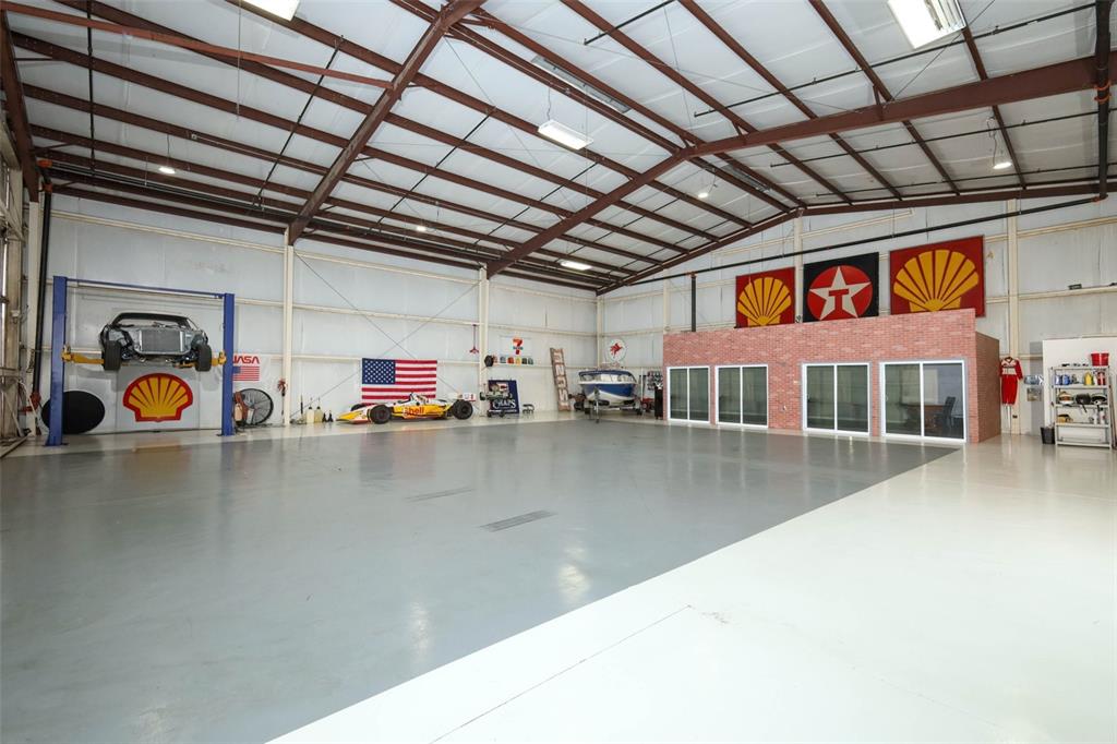 A large garage space features a car lift, a race car, a boat, and wall decor — 1312 APOPKA AIRPORT ROAD, APOPKA, FL