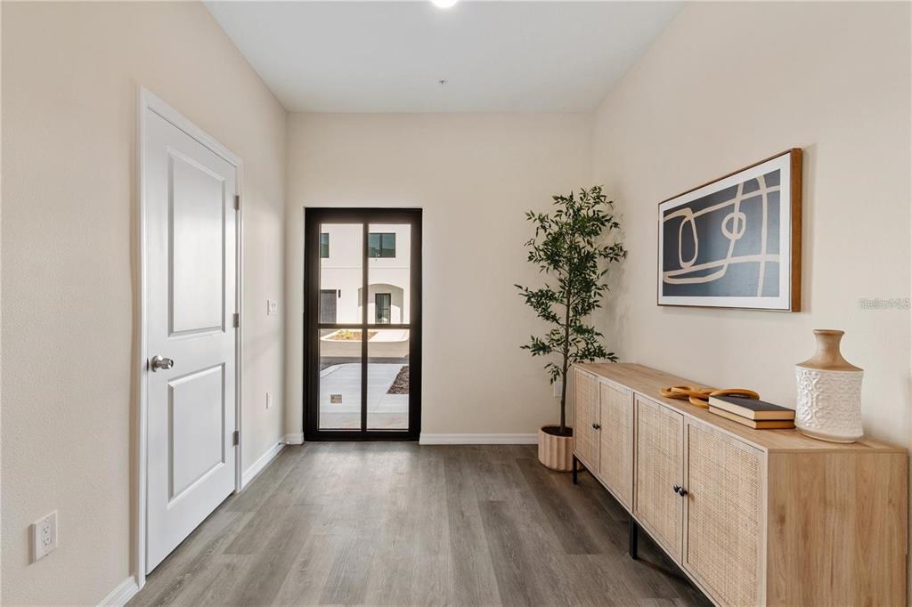An entryway features light wood-look flooring, a white door, a glass-paned door, and a sideboard — 4367 CAMBIO GARDENS COURT, TAMPA, FL