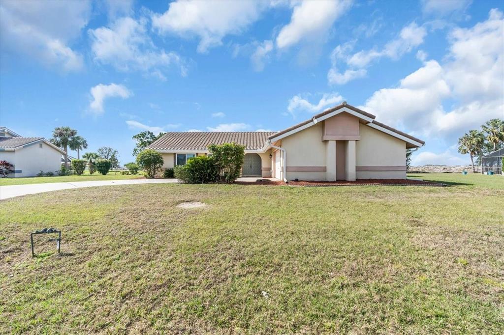 A single-story house with a beige exterior and a tiled roof sits on a lawn — 5061 RICHMOND TERRACE, NORTH PORT, FL