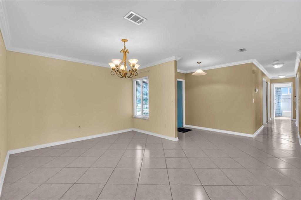 An empty dining room with tile flooring, a chandelier, and a hallway leading to rooms — 5061 RICHMOND TERRACE, NORTH PORT, FL