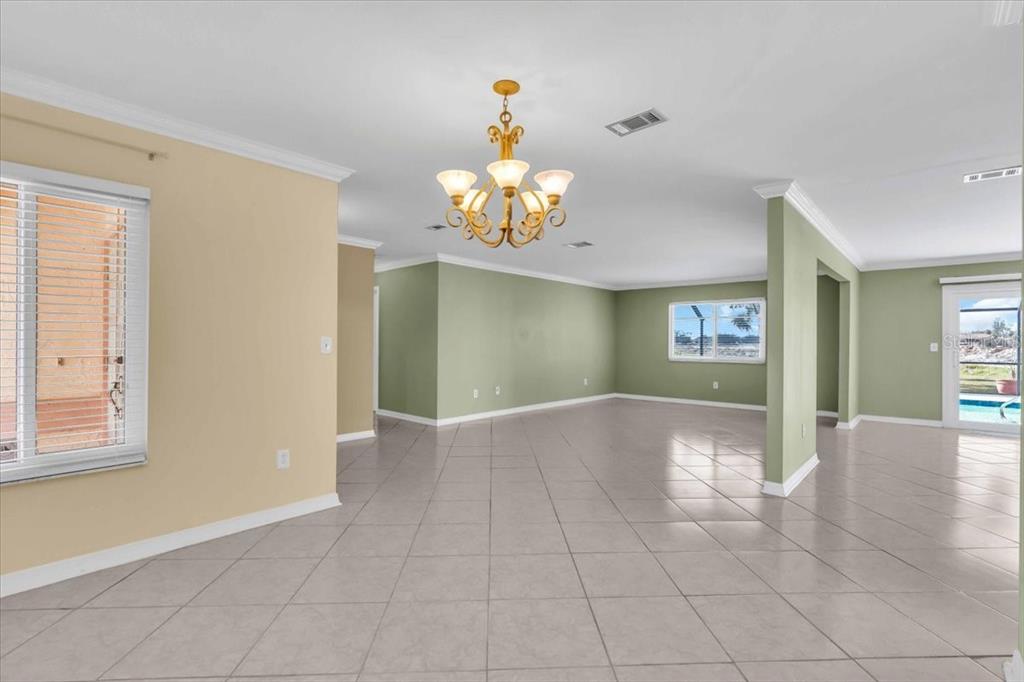 An open-concept living area features light-colored tile flooring, sage green walls, and a gold chandelier — 5061 RICHMOND TERRACE, NORTH PORT, FL