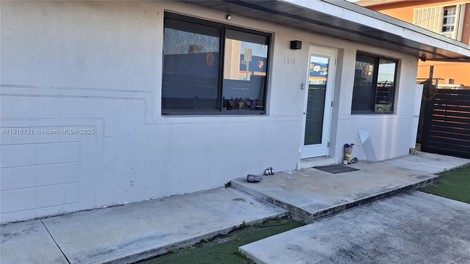 The exterior of a single-story building features a white stucco facade, a front door, and windows — 3510 NW 33rd Ave, Miami FL 33142, MIAMI, FL