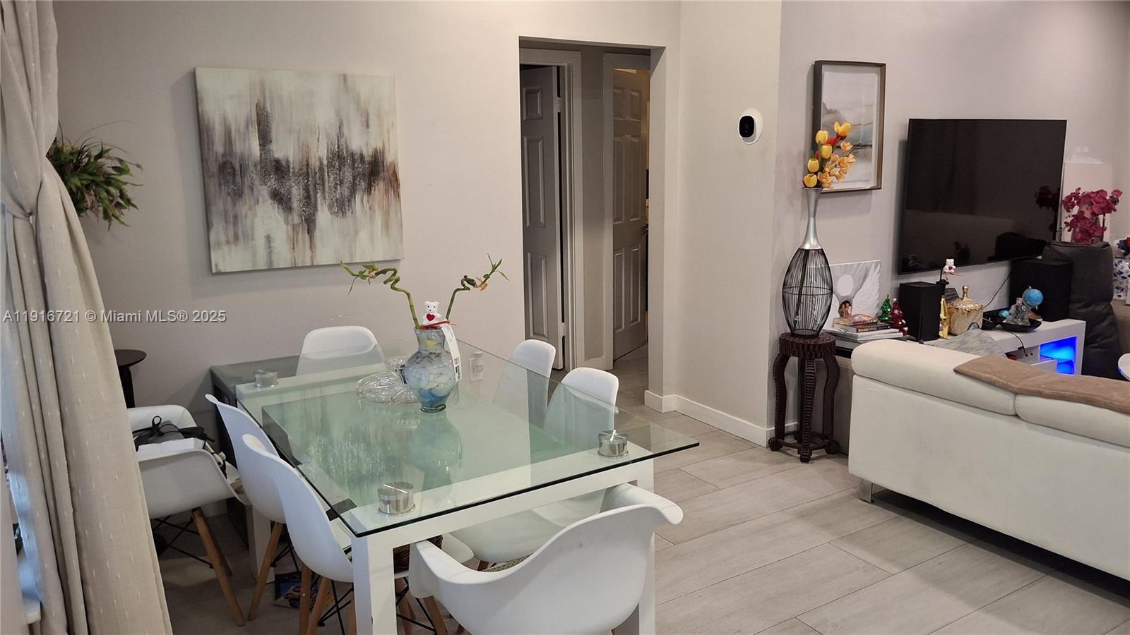 A dining area with a glass table and white chairs sits adjacent to a living room — 3510 NW 33rd Ave, Miami FL 33142, MIAMI, FL