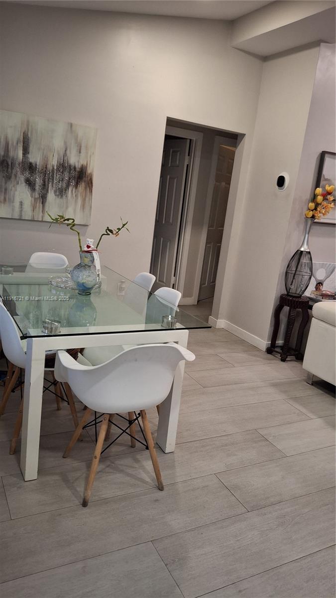 A dining room features a glass-topped table with white chairs and light wood-look tile flooring — 3510 NW 33rd Ave, Miami FL 33142, MIAMI, FL