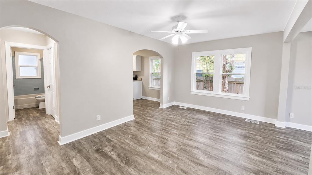 A living room with gray wood-look flooring, arched doorways, and a ceiling fan — 657 15TH AVENUE S, ST PETERSBURG, FL