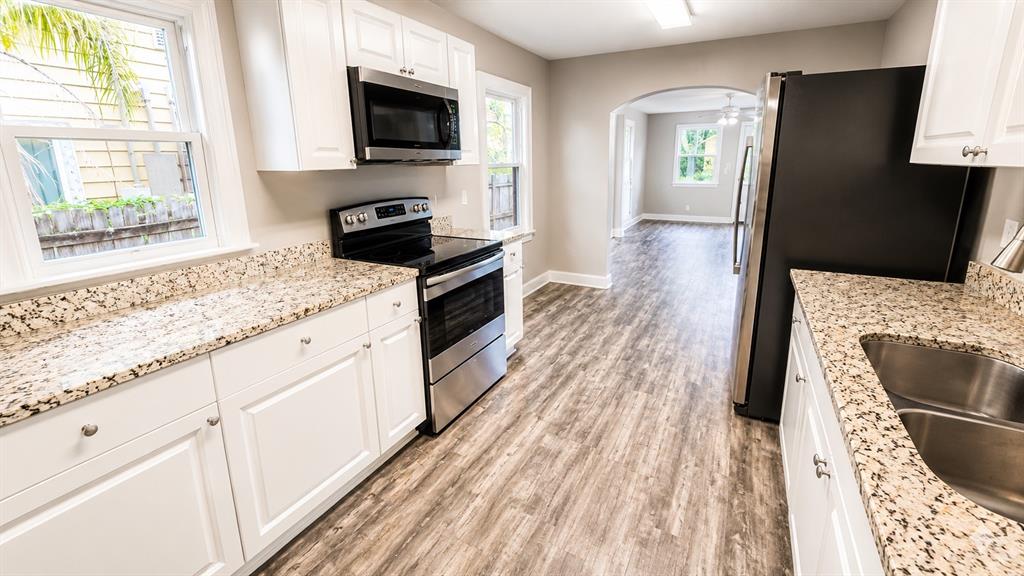 A kitchen features white cabinets, granite countertops, stainless steel appliances, and wood-look flooring — 657 15TH AVENUE S, ST PETERSBURG, FL