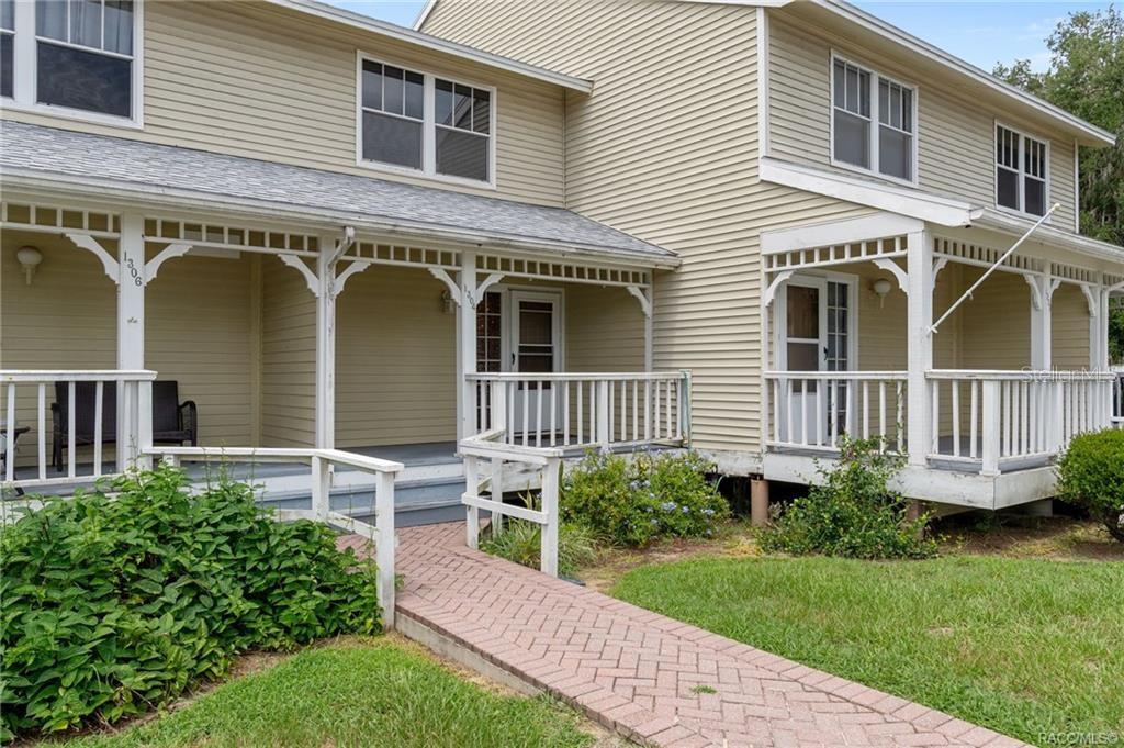 A two-story building with beige siding features two front porches and a brick walkway — 1304 CYPRESS COVE COURT, INVERNESS, FL