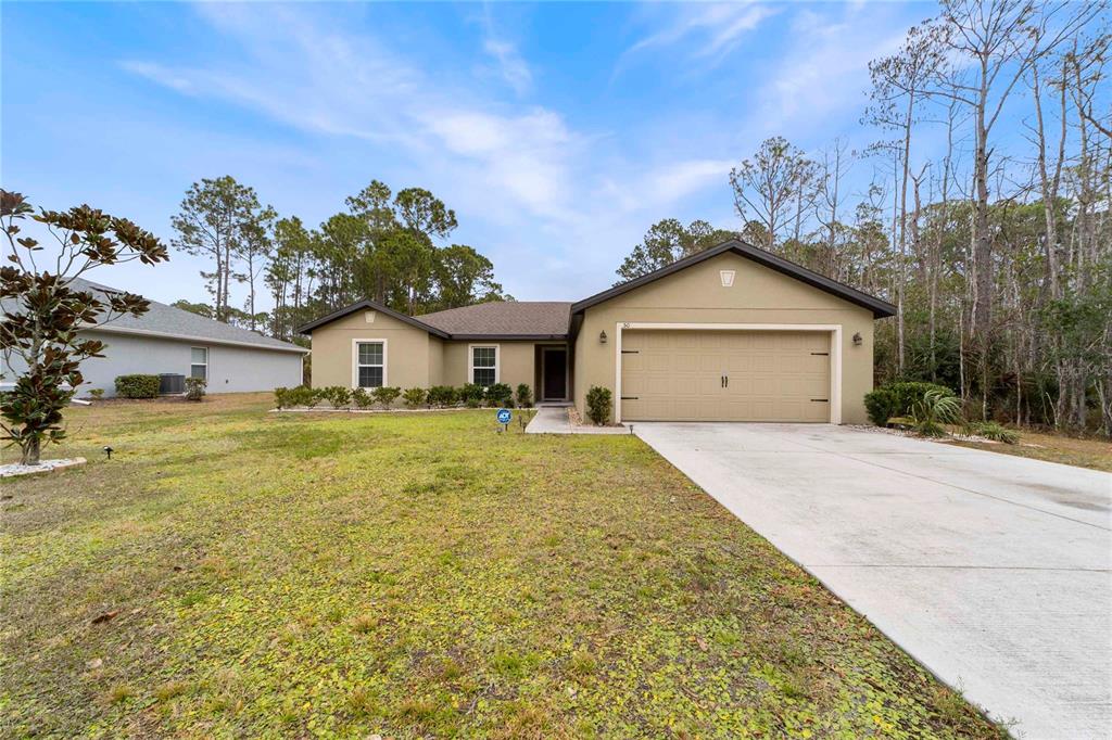 A single-story house with a tan stucco exterior, a two-car garage, and a concrete driveway — 50 ULLIAN TRAIL, PALM COAST, FL