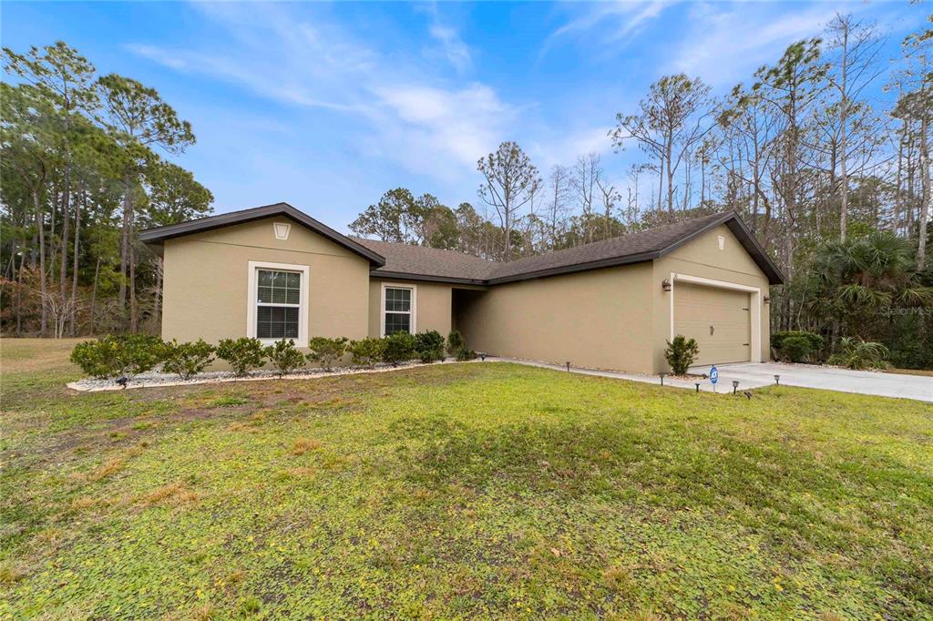 A single-story tan house with a two-car garage sits on a grassy lot — 50 ULLIAN TRAIL, PALM COAST, FL