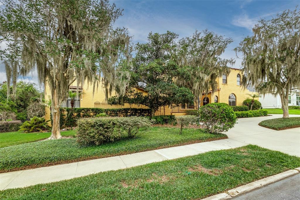 A yellow two-story house with Spanish-style architecture sits behind trees draped in Spanish moss — 327 MIRAMAR ROAD, LAKELAND, FL