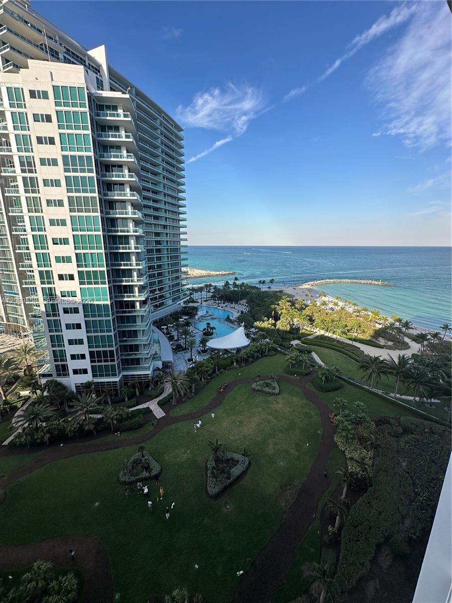 An elevated view of a high-rise building, a swimming pool, a grassy lawn, and the ocean — BAL HARBOUR, FL