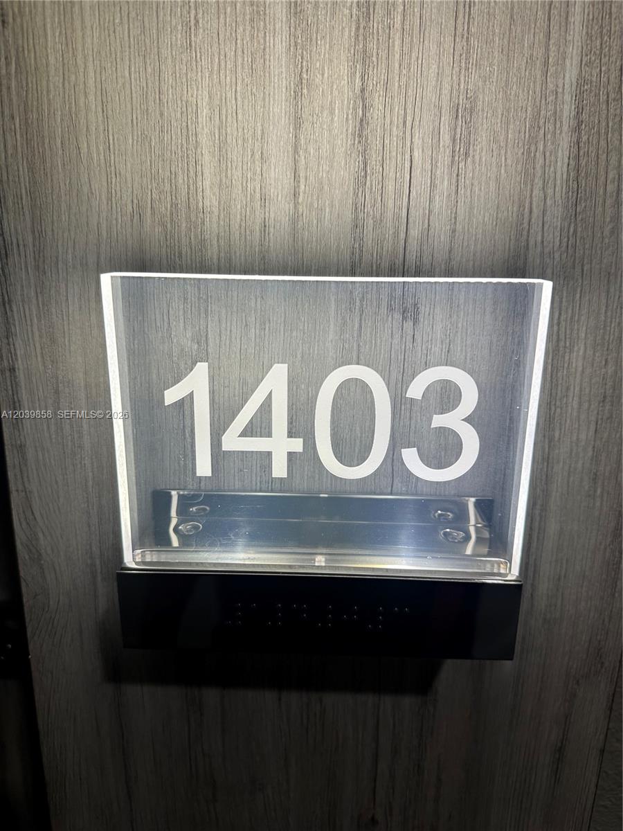 A backlit acrylic sign displaying the number 1403 is mounted on a wood-grain door — BAL HARBOUR, FL