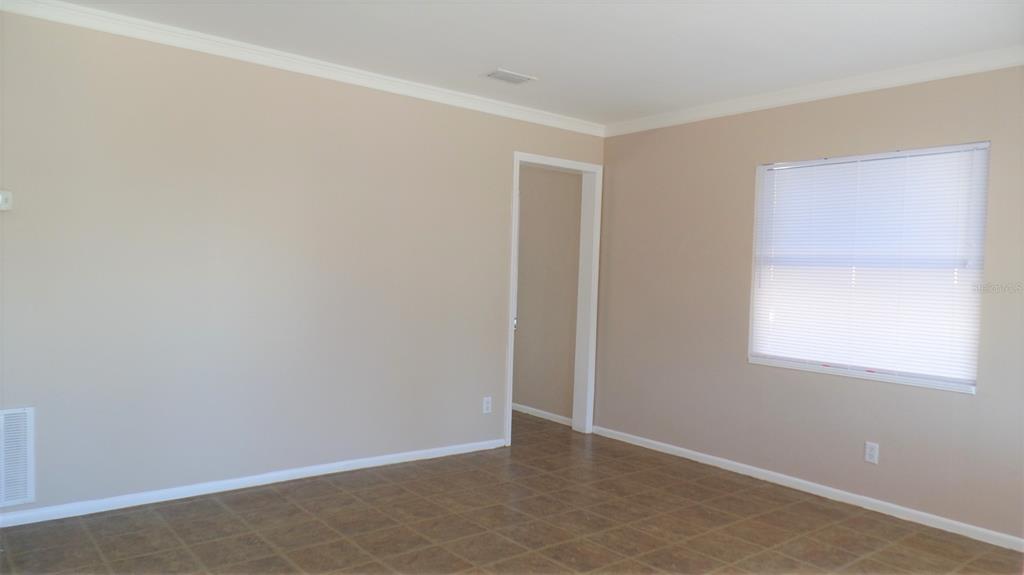 An empty room features beige walls, white trim, a tiled floor, and a single window — 4935 EMERSON AVENUE S, ST PETERSBURG, FL