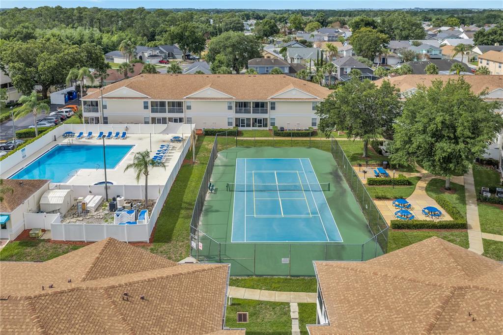 An aerial view shows a swimming pool and a tennis court between two apartment buildings — 8810 GRAND PALMS CIRCLE UNIT B, KISSIMMEE, FL