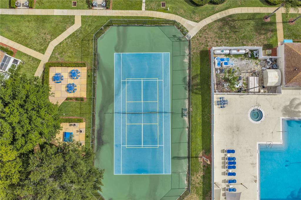 An aerial view shows a fenced tennis court next to a swimming pool and patio area — 8810 GRAND PALMS CIRCLE UNIT B, KISSIMMEE, FL