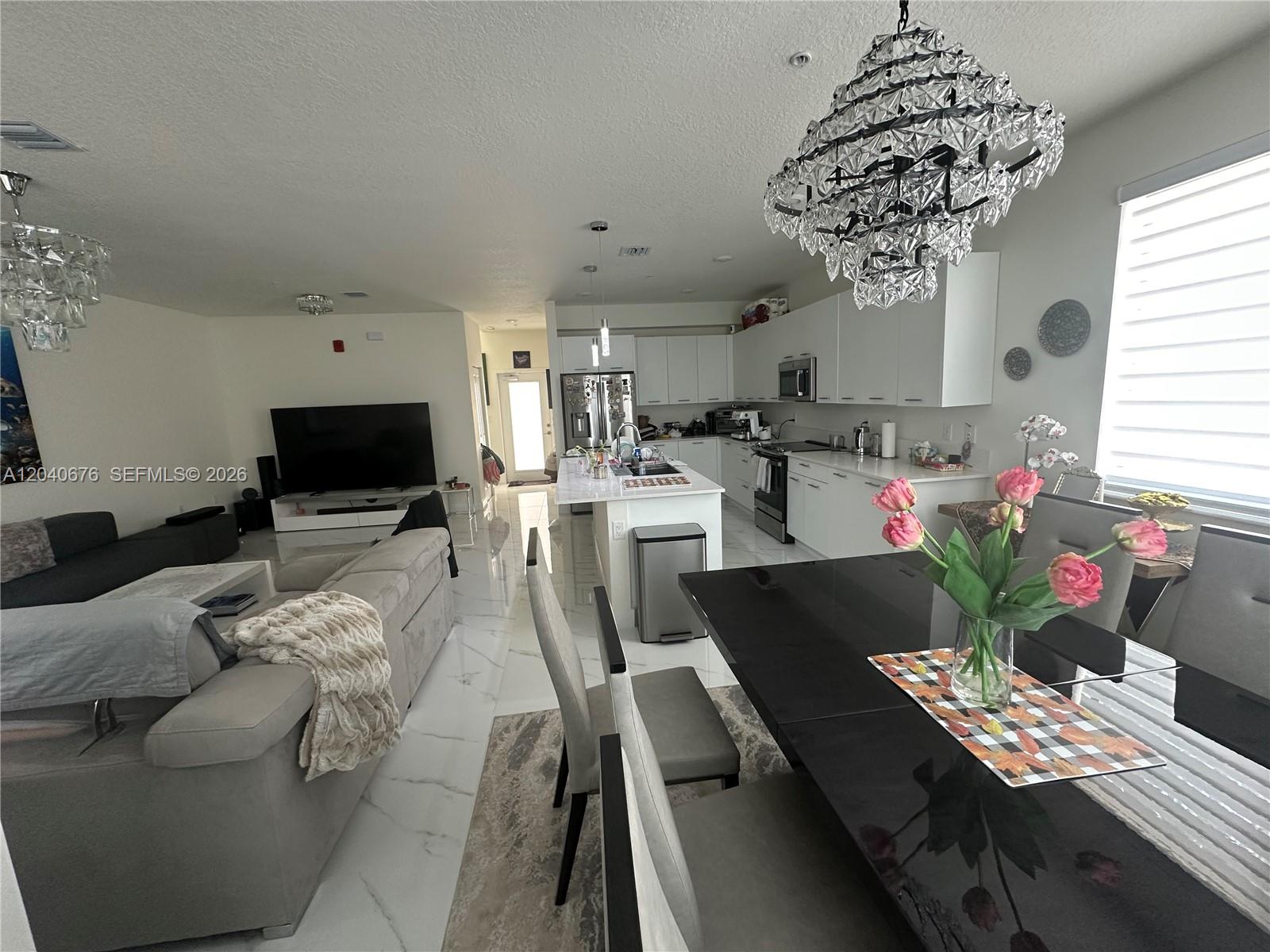 An open-concept living area features a kitchen with white cabinets, an island, and dining space — 8001 NW 41st St # 113, Doral FL 33166, DORAL, FL