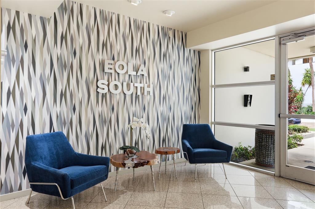 A lobby features two blue armchairs, two wood-slice tables, and a patterned wall with signage — 1 S EOLA DRIVE UNIT 13, ORLANDO, FL