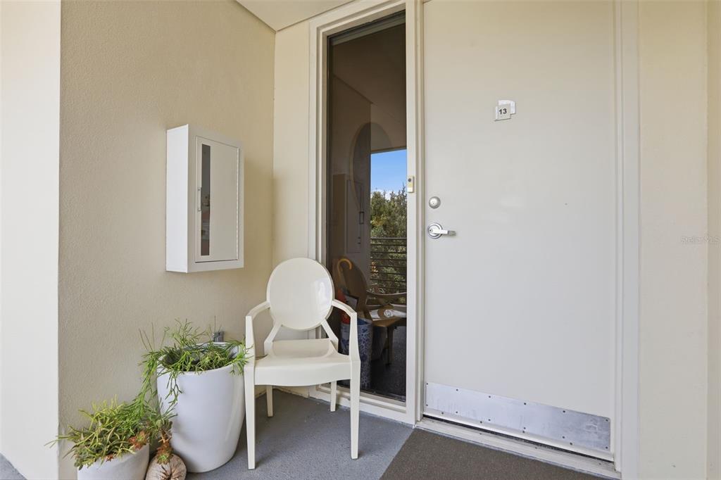 A white door with number 13, a white chair, and a potted plant on a balcony — 1 S EOLA DRIVE UNIT 13, ORLANDO, FL