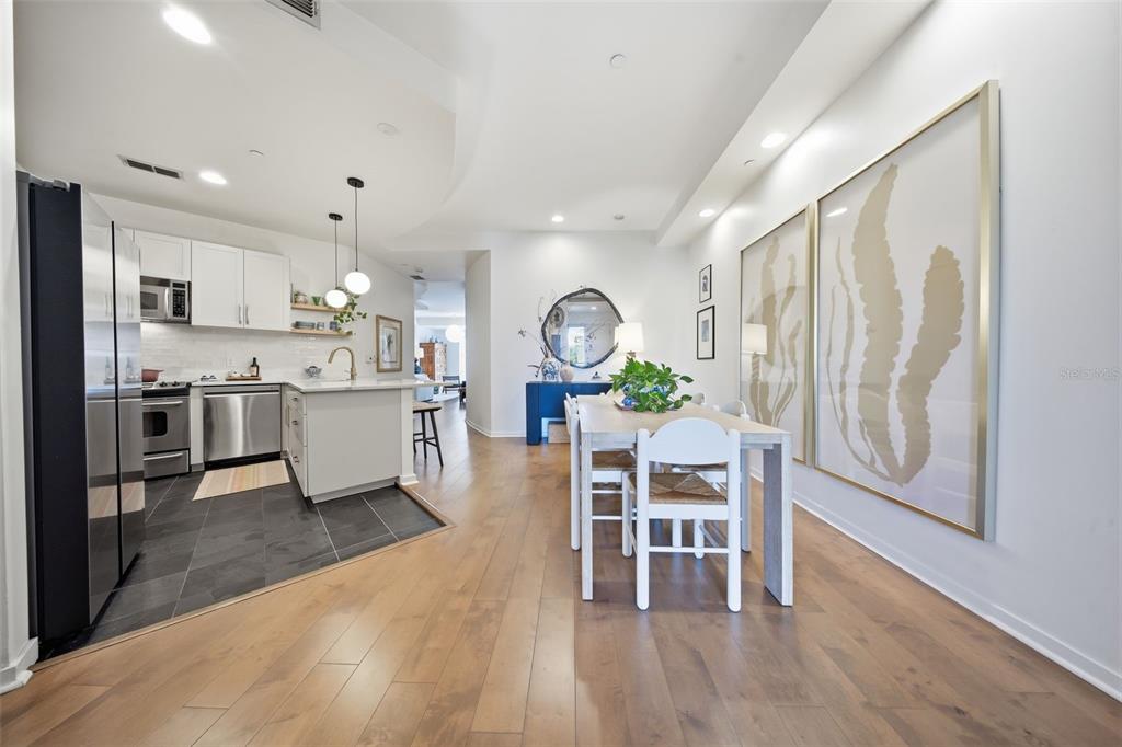 A kitchen with white cabinets and a dining area with a table and wall art — 1 S EOLA DRIVE UNIT 13, ORLANDO, FL