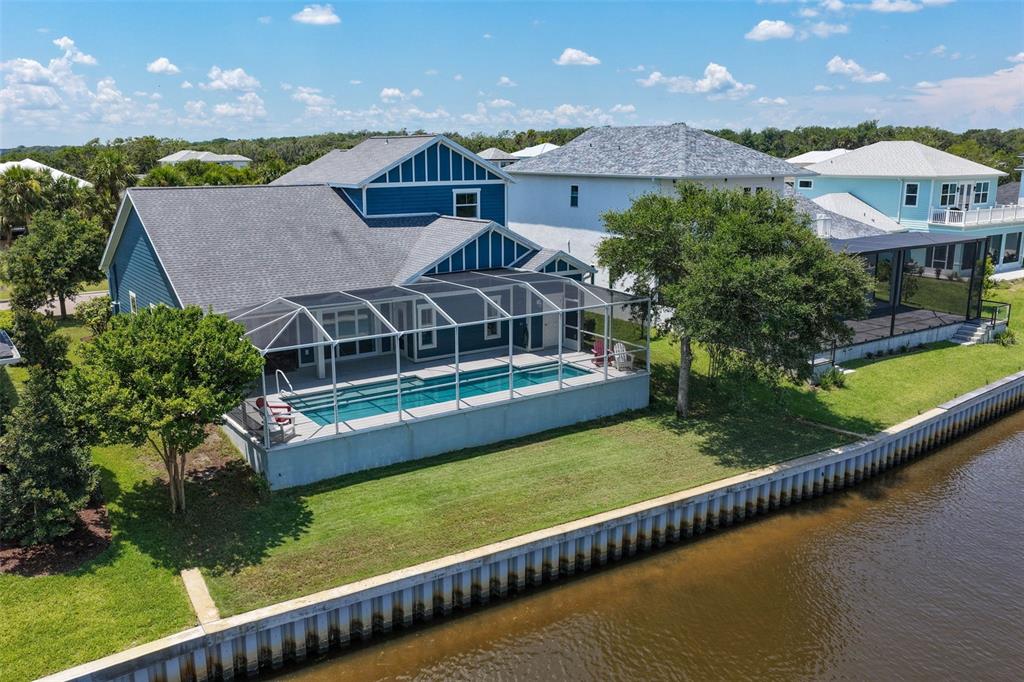 An aerial view of a blue house with a screened-in pool overlooking a canal — 127 SEASIDE POINT, FLAGLER BEACH, FL