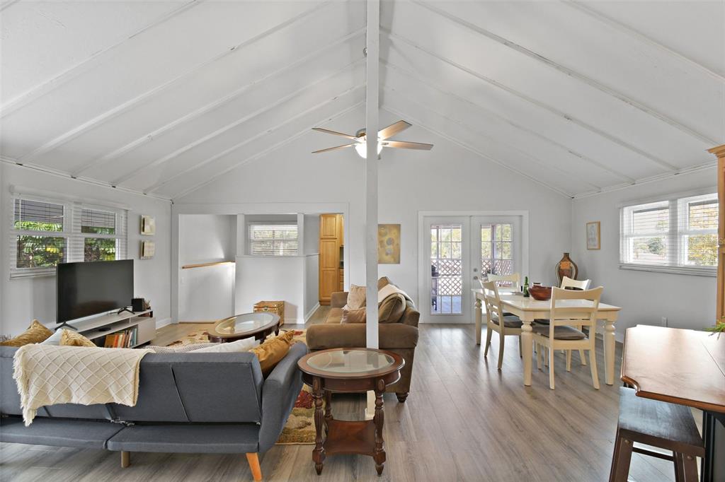 A living and dining room with a vaulted ceiling, wood-look flooring, and a central post — 46 WINDY HILL LANE, BABSON PARK, FL