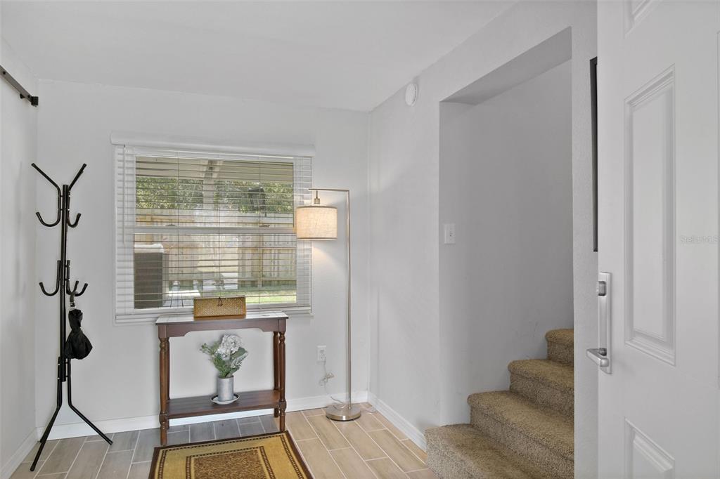 An entryway features tile flooring, a coat rack, a console table, and carpeted stairs — 46 WINDY HILL LANE, BABSON PARK, FL