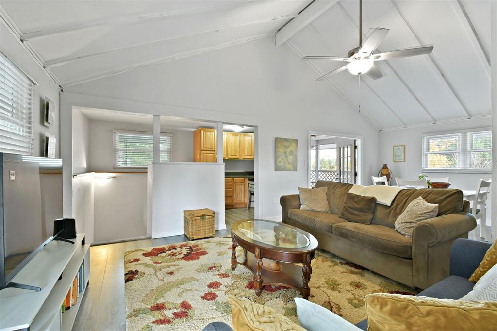 A living room features a vaulted ceiling, a brown sofa, and an open kitchen area — 46 WINDY HILL LANE, BABSON PARK, FL