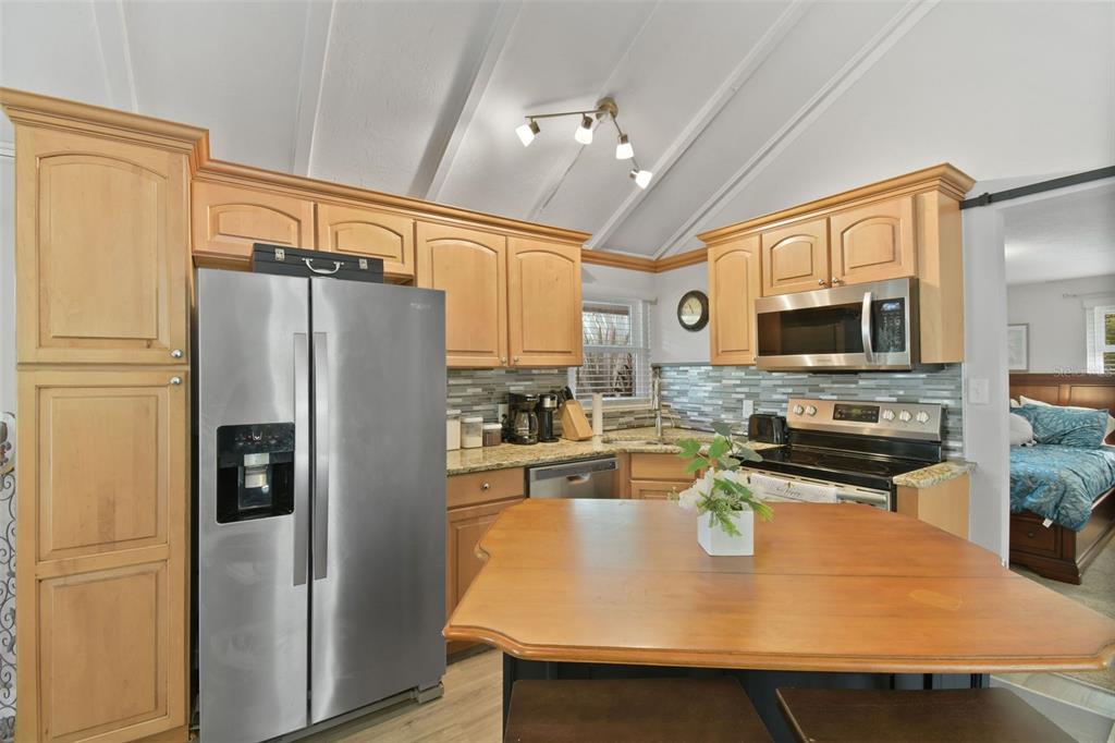 A kitchen with light wood cabinets, stainless steel appliances, and a wooden island — 46 WINDY HILL LANE, BABSON PARK, FL