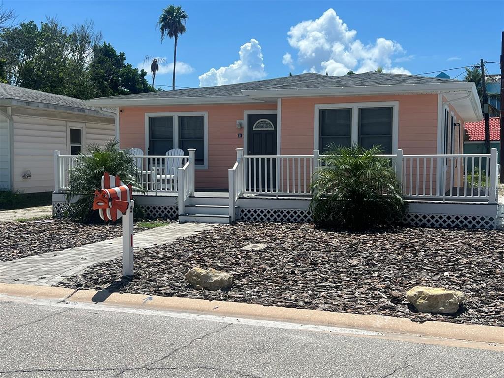 A peach-colored single-story house features a white porch, a clownfish-shaped mailbox, and a rock-covered yard — 5 82ND AVENUE, TREASURE ISLAND, FL