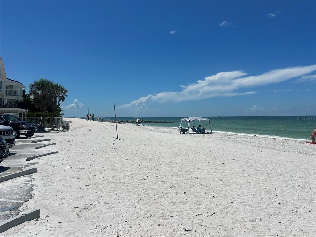 A sandy beach with parked cars, a striped canopy, and the ocean under a blue sky — 5 82ND AVENUE, TREASURE ISLAND, FL