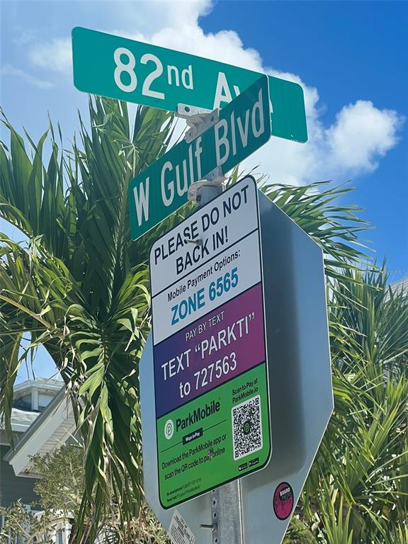 A street sign for 82nd Avenue and W Gulf Blvd sits above a parking information sign — 5 82ND AVENUE, TREASURE ISLAND, FL