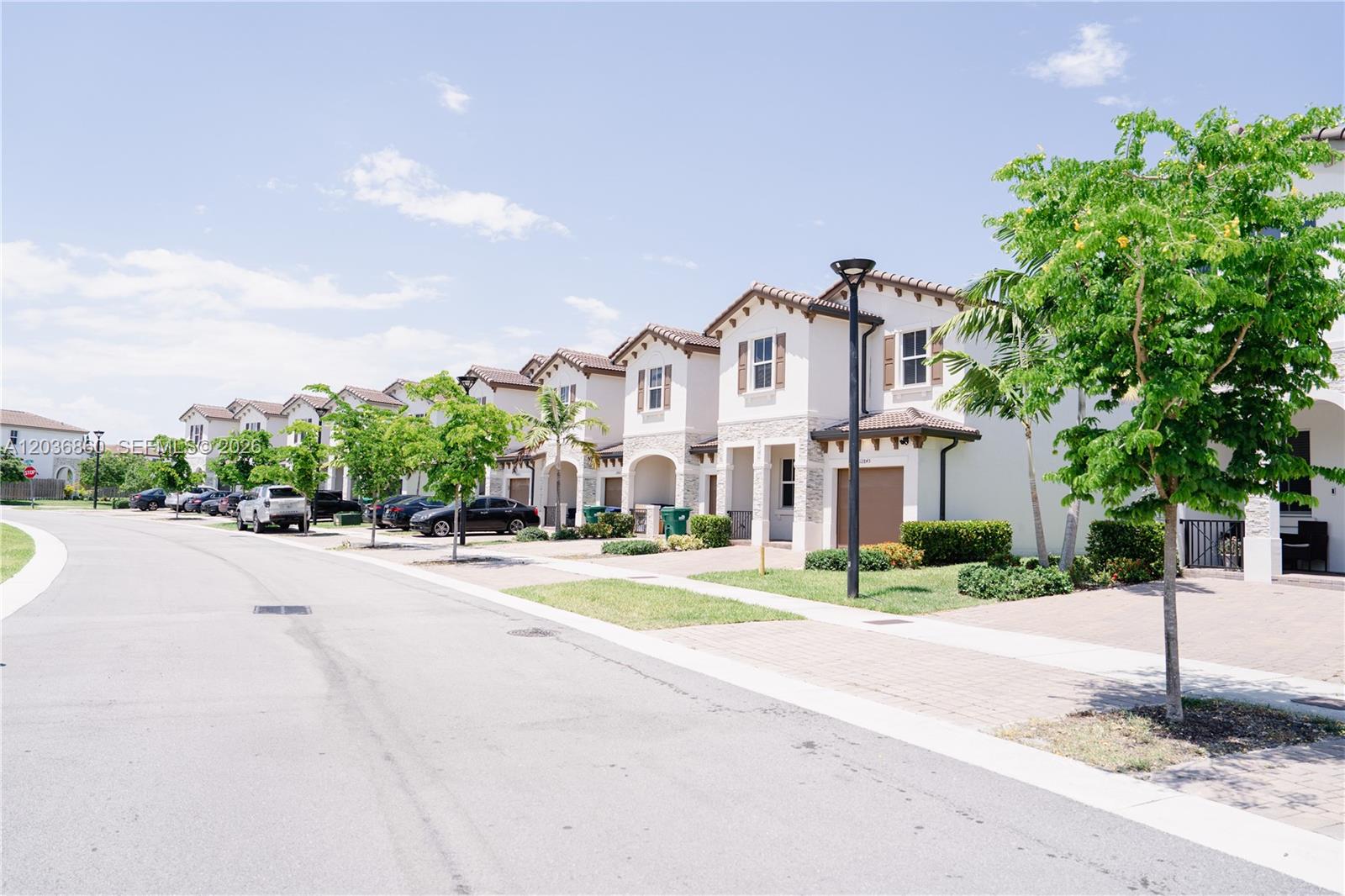 A row of two-story stucco townhouses with tiled roofs lines a paved residential street — 12779 NW 24th Ave # 0, Miami FL 33167, MIAMI, FL