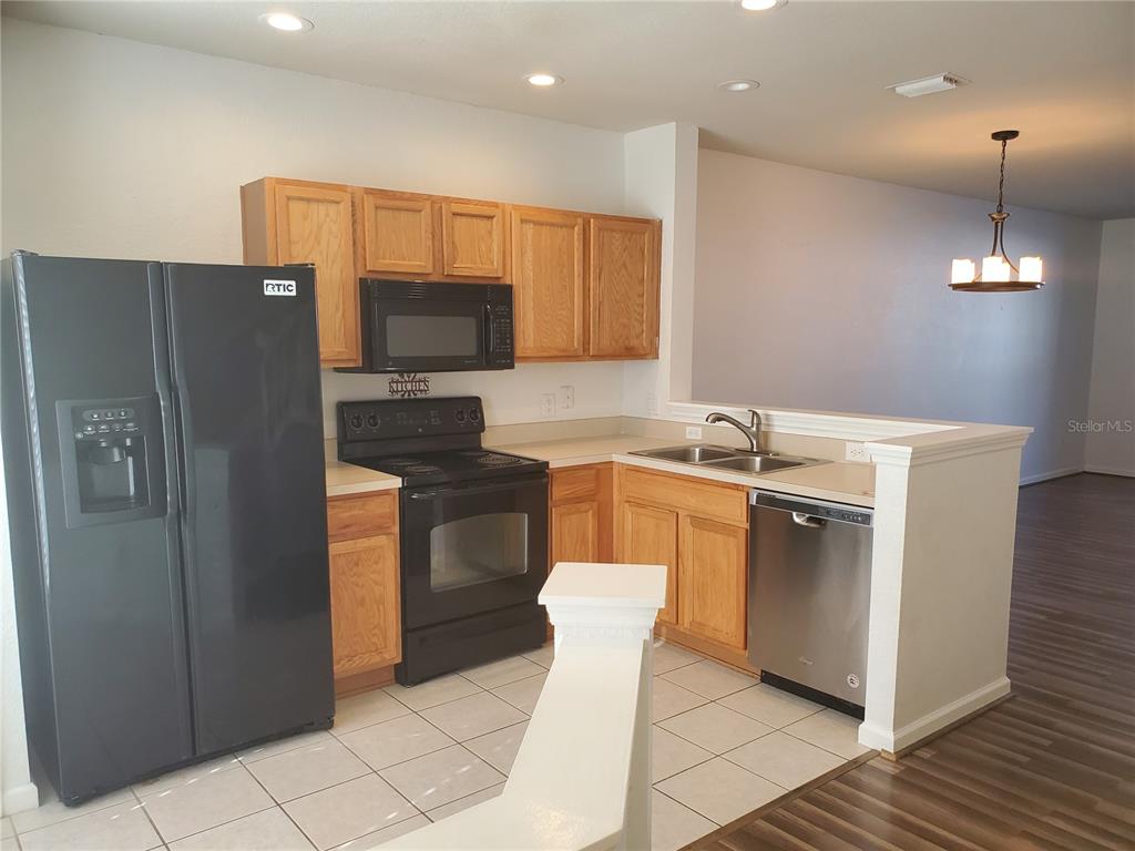 A kitchen with light wood cabinets, black appliances, a stainless dishwasher, and tile flooring — 4480 SW 49TH AVENUE, OCALA, FL