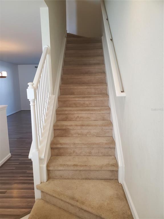 A carpeted staircase with a white wooden railing leads to an upper level — 4480 SW 49TH AVENUE, OCALA, FL