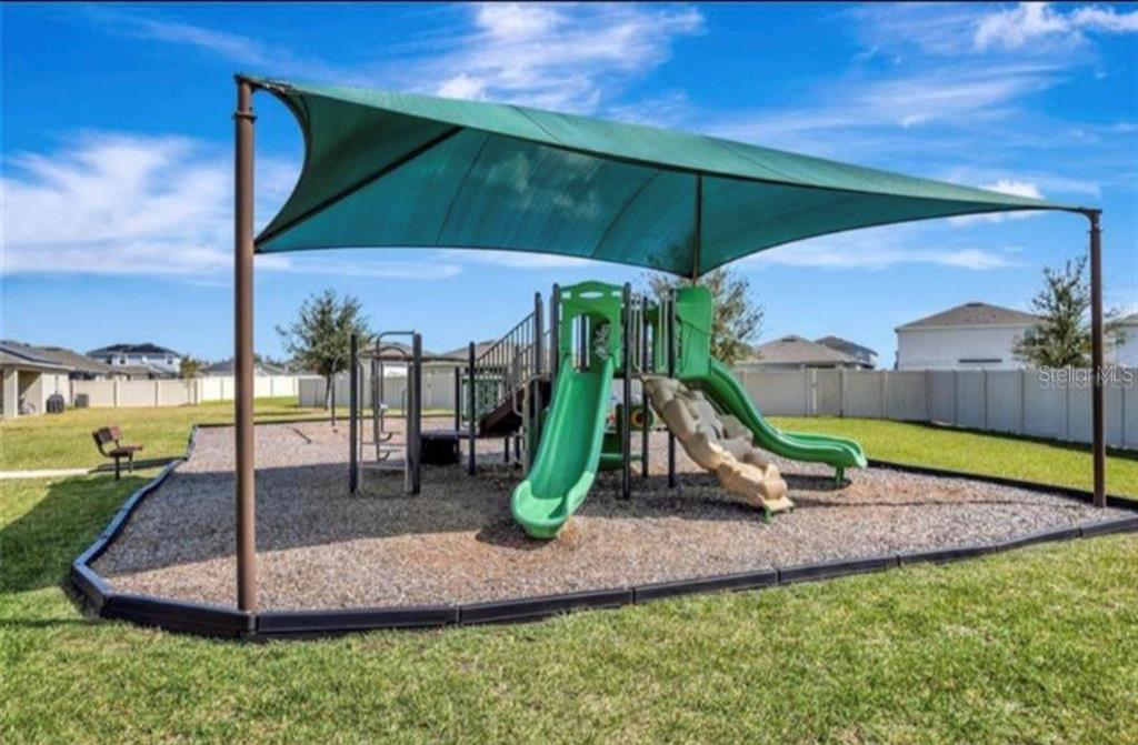 A playground with slides and a shade canopy sits on a gravel base outdoors — 244 HAMLET LOOP, DAVENPORT, FL