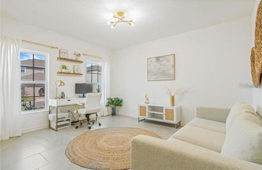 A bright home office features a desk, sofa, round jute rug, and light tile flooring — 244 HAMLET LOOP, DAVENPORT, FL