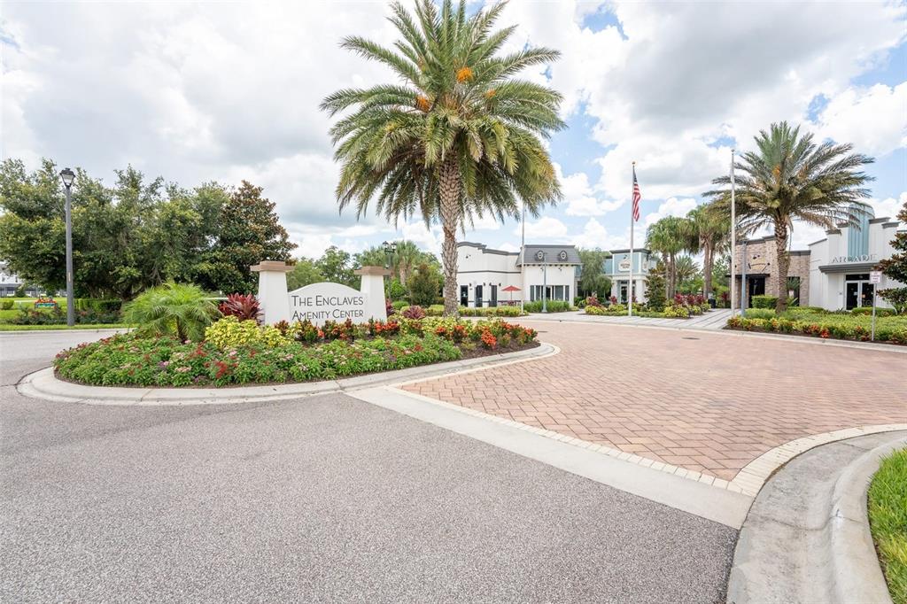 The entrance to The Enclaves Amenity Center features a landscaped sign, palm trees, and buildings — 1038 PLANTATION LANE, DAVENPORT, FL