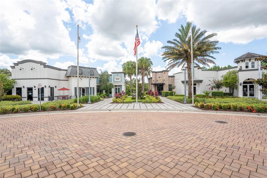 A paved circular driveway leads to a commercial building complex with palm trees and flags — 1038 PLANTATION LANE, DAVENPORT, FL