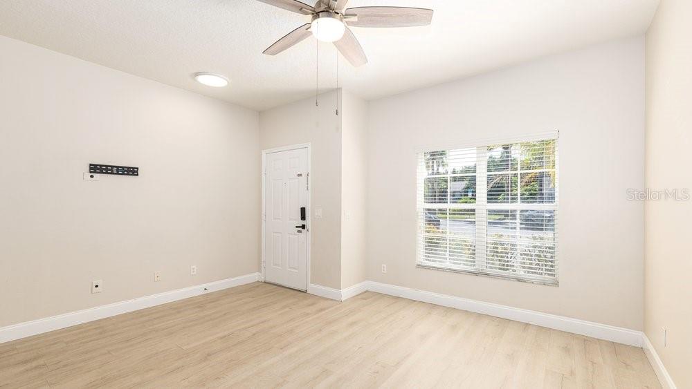An empty room with light wood-look flooring, a ceiling fan, a window, and a door — 10020 REGENT PARK DRIVE UNIT 2405, ORLANDO, FL