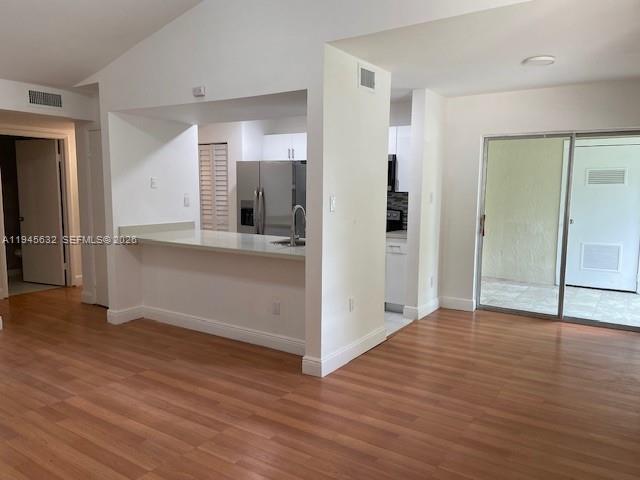 An open-concept kitchen with a breakfast bar overlooks a living area with wood-look flooring — 15325 SW 106th Ter # 618, Miami FL 33196, MIAMI, FL