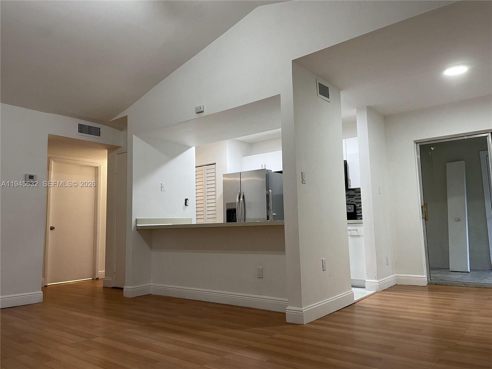 A kitchen with a breakfast bar opens into a living area with wood-look flooring — 15325 SW 106th Ter # 618, Miami FL 33196, MIAMI, FL