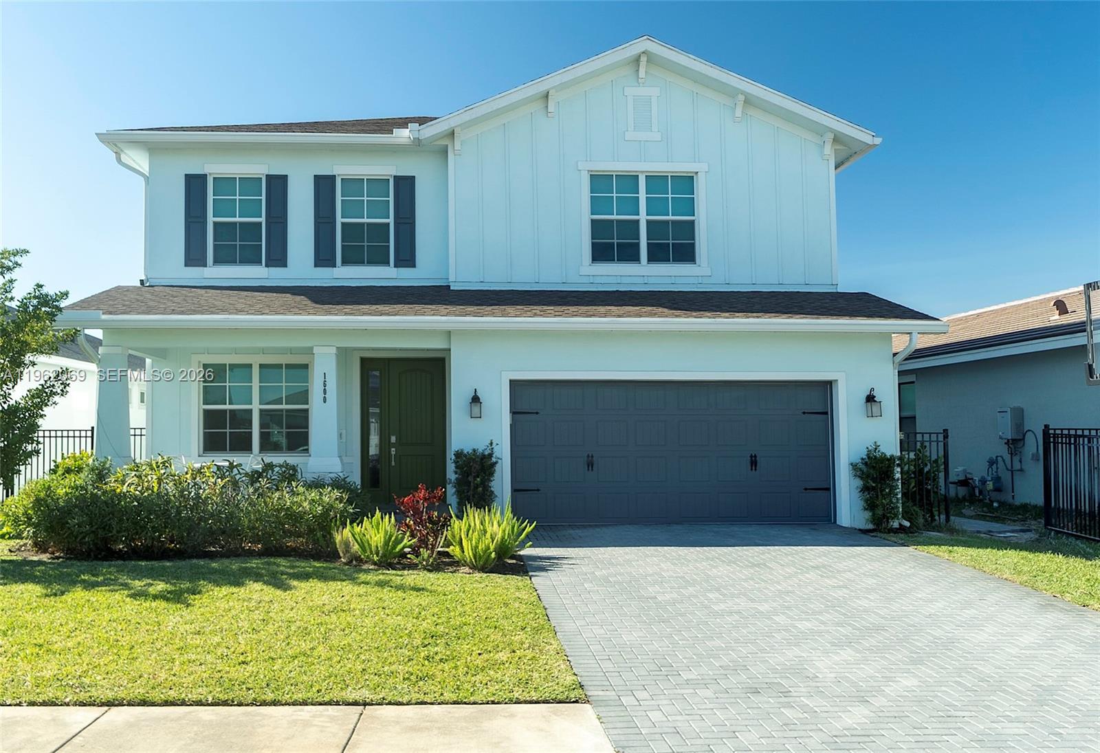 A two-story house with light blue siding, a gray garage door, and a paved driveway — 1600 Wandering Willow Way, Loxahatchee FL 33470, LOXAHATCHEE, FL