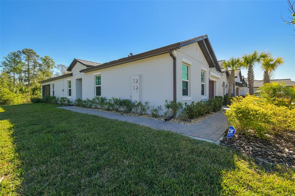 A side view of a light-colored stucco house with a paved walkway and landscaping — 16710 SHELL BAY DRIVE, LAND O LAKES, FL
